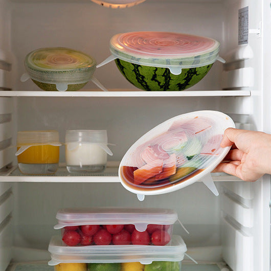 Hand opening a refrigerator door with a container of food inside.
